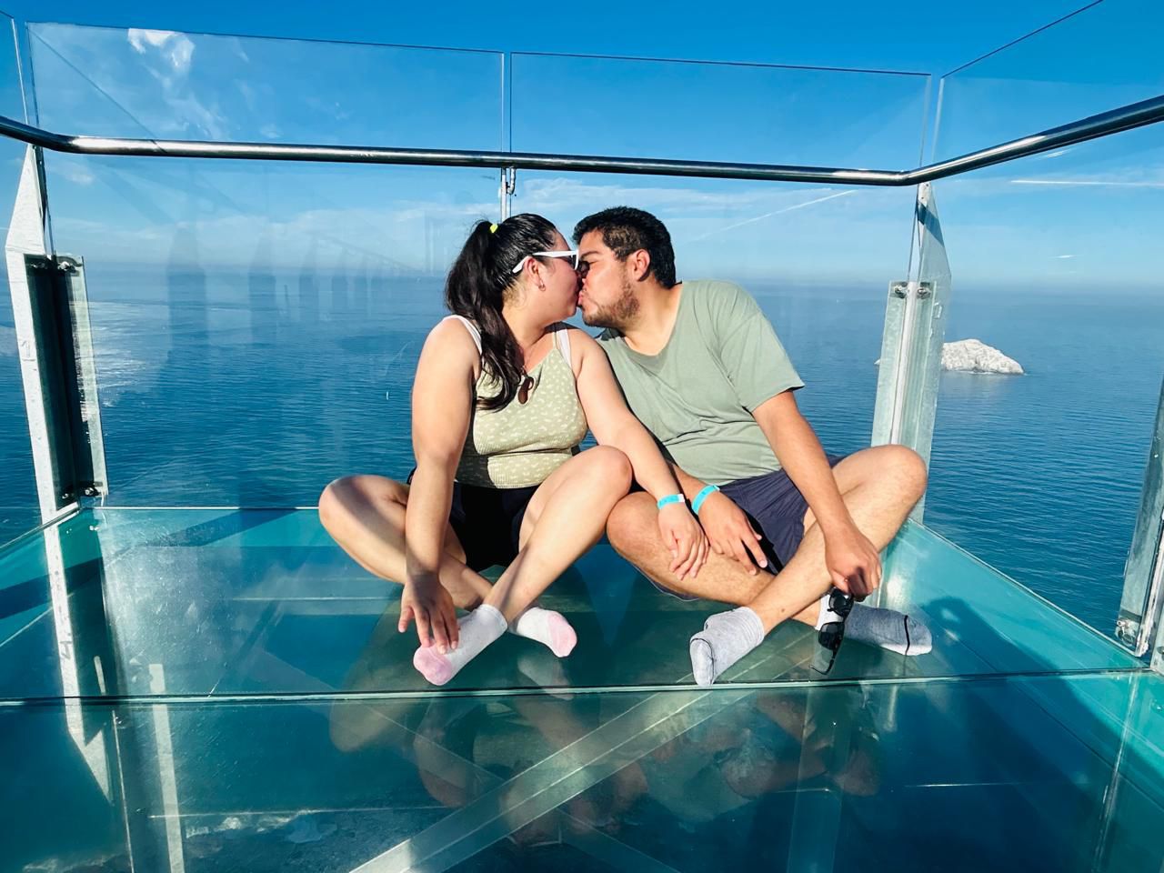 Pareja disfrutando de un mirador de cristal sobre el mar
