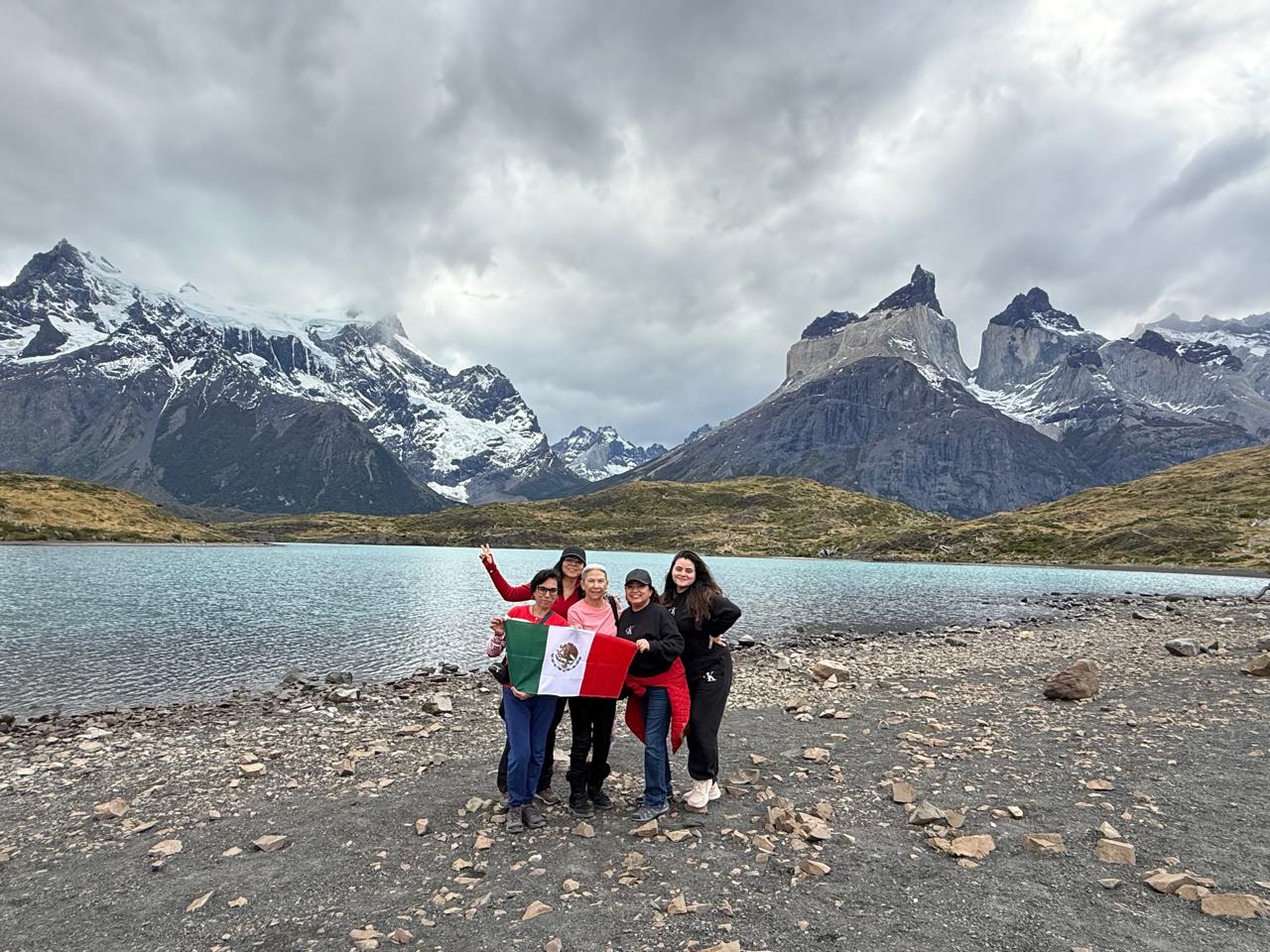 Grupo de viajeras con bandera mexicana frente a las montañas de la Patagonia